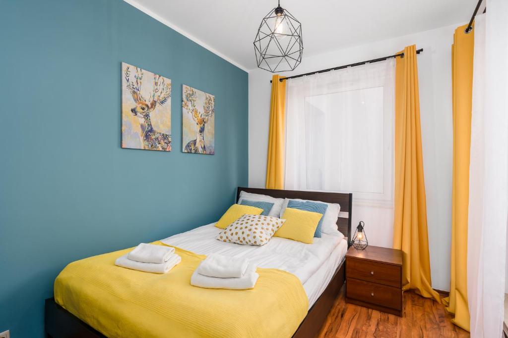 sypialnia z łóżkiem z żółtymi i niebieskimi ścianami w obiekcie Sleepway Apartments - Garbary 95-75D w Poznaniu