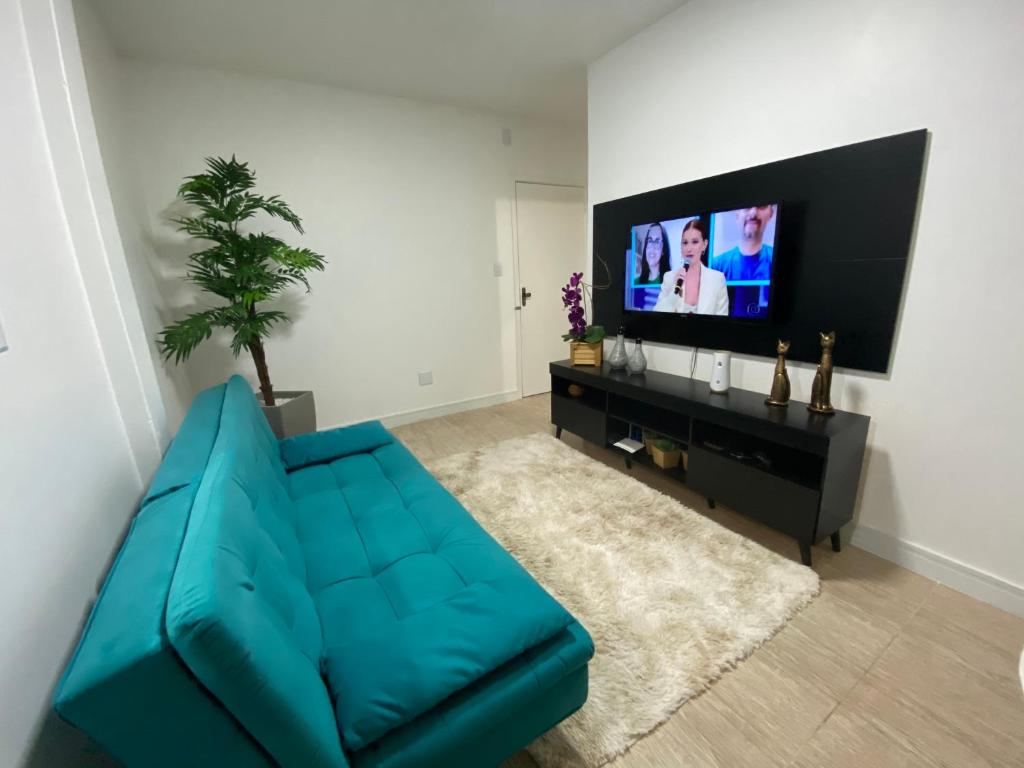 un soggiorno con un divano blu e una TV a schermo piatto di Ap 304 - Beira mar - pés na areia a Capão da Canoa