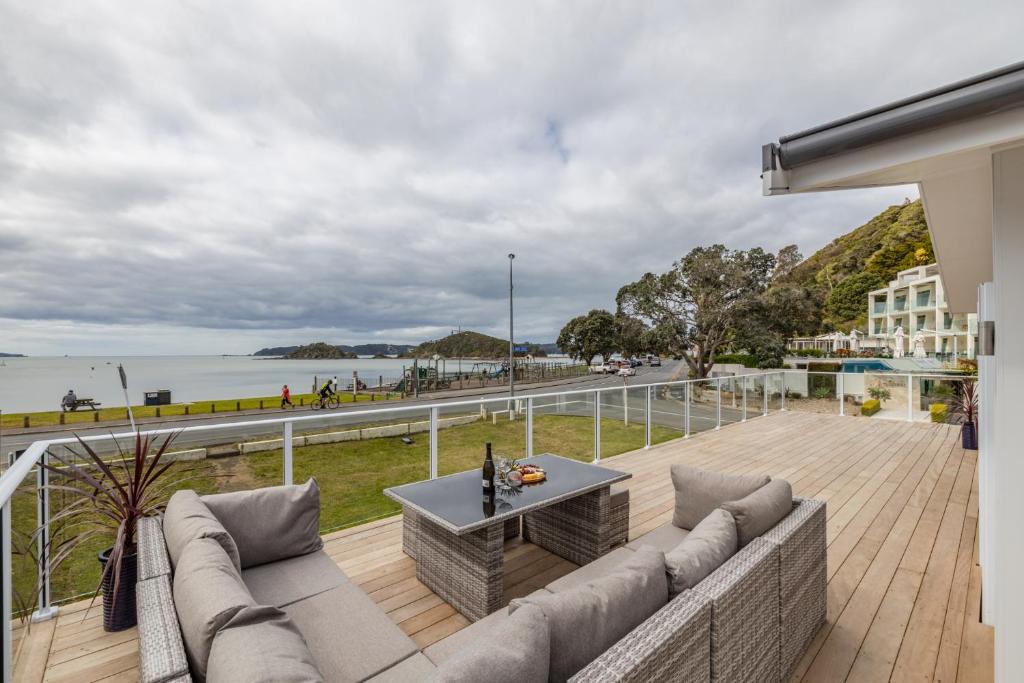 a balcony with a couch and a view of the ocean at Waterfront Beach House - Paihia Holiday Home in Paihia
