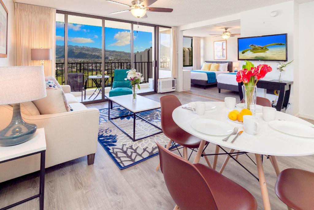 een woonkamer met een witte tafel en stoelen bij Warm Aloha Vibes, Mountain Views, Short Walk to Beach, and Free Parking in Honolulu