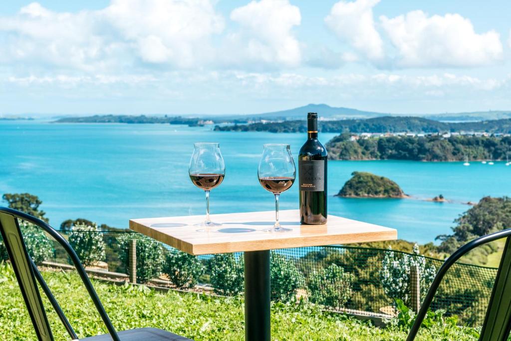 una bottiglia di vino e due bicchieri su un tavolo di The Apartment - Sea Views at Te Whau Point by Waiheke Unlimited a Omiha