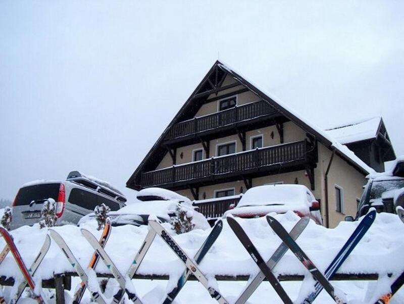 a snow covered house with cars parked in front of it at Monte Negro in Stronie Śląskie