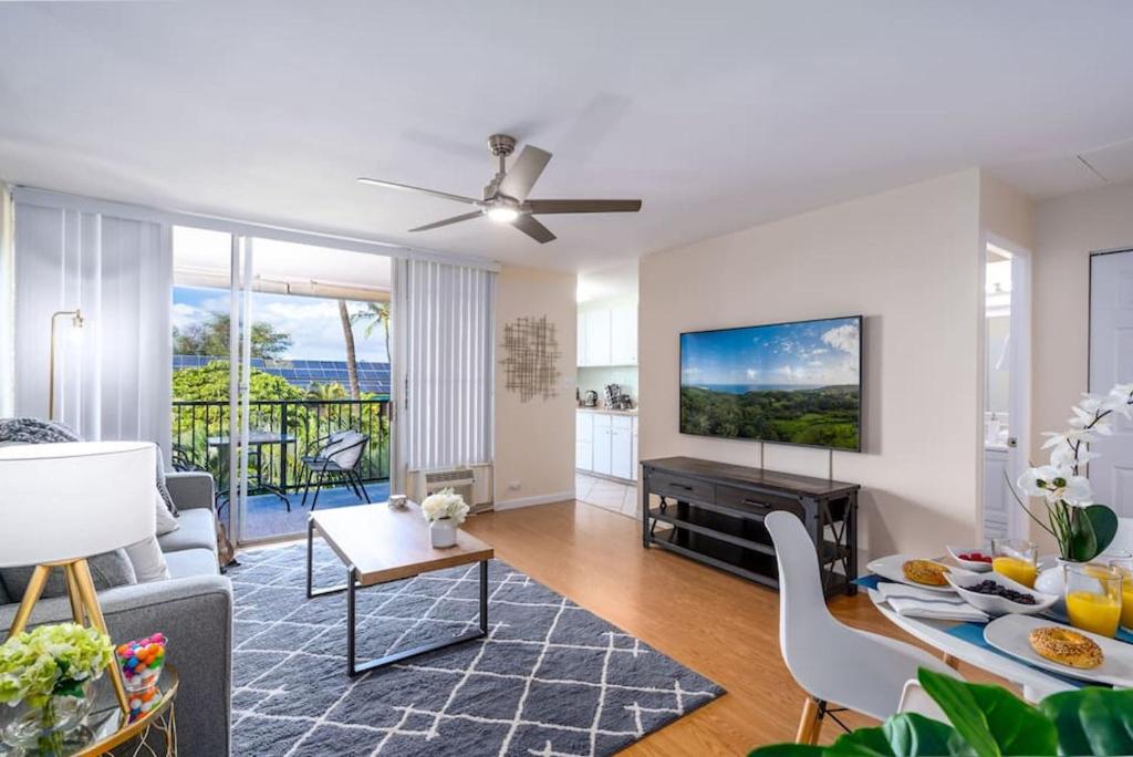 a living room with a couch and a tv at Top Floor Ocean Views Condo in Kihei