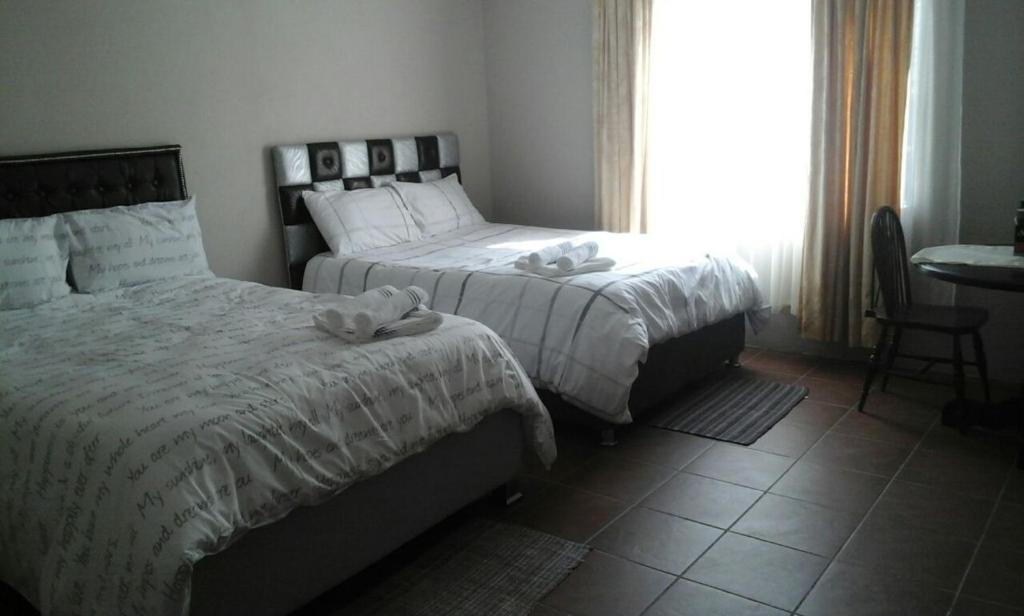 a bedroom with two beds and a table and a window at SIMA SILVER LODGE in Tzaneen