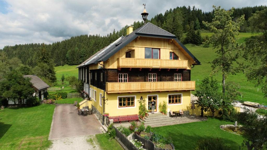 una gran casa de madera en una colina verde con árboles en Pernerhof en Mariapfarr