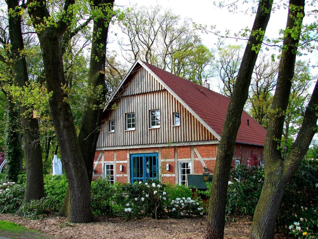a red barn with a blue door and trees at Ferienwohnung Lodberger Scheunencafe in Löningen