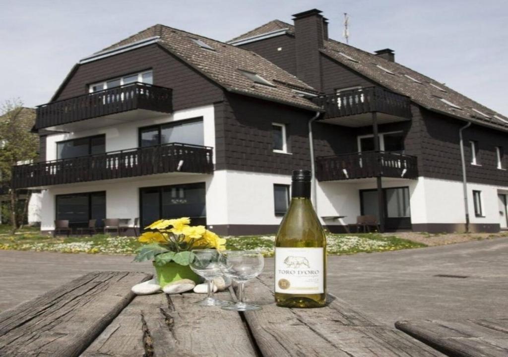Una botella de vino y dos copas en una mesa de madera. en Ferienpark Winterberg en Winterberg