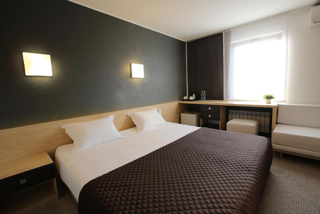 ビシュケクにあるフトゥロホテル ビシュケクの大きなベッドと窓が備わるホテルルームです。
