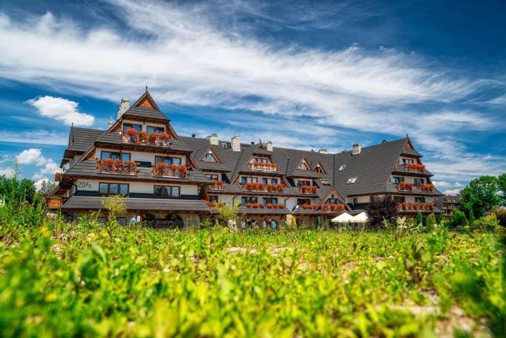 ein großes Gebäude mit vielen Fenstern auf einem Feld in der Unterkunft Pensjonat pod Kotelnicą in Białka Tatrzańska