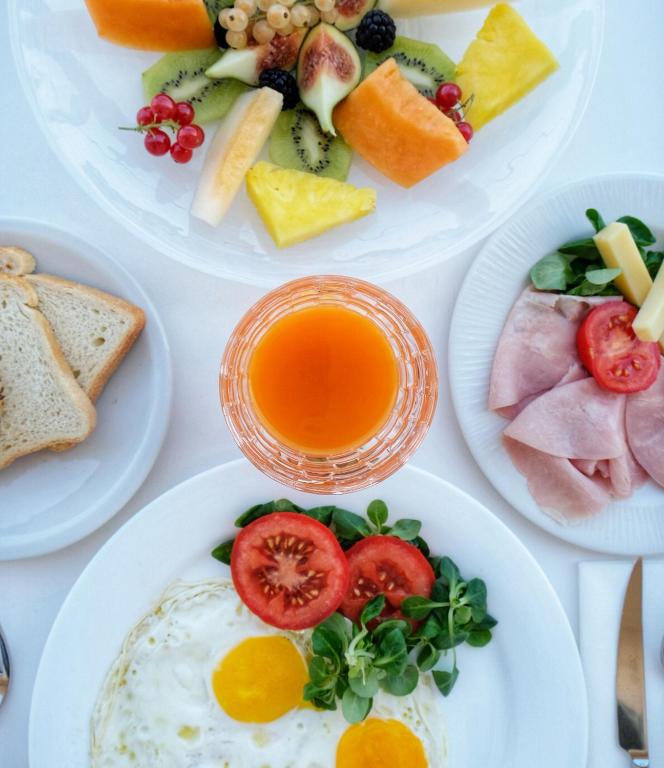 a table with plates of breakfast foods and a glass of orange juice at JR Hotels Bari Grande Albergo delle Nazioni in Bari