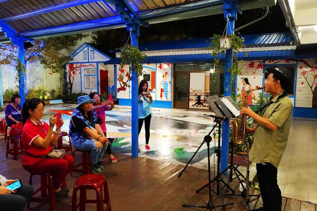 un hombre tocando un saxofón delante de un grupo de personas en 儷福花園山莊Lifu Garden Inn, en Hualing