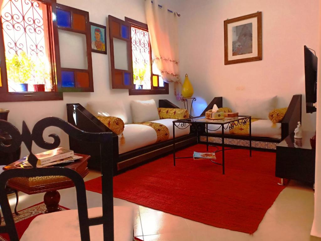 uma sala de estar com um sofá e um tapete vermelho em DAR AZIZ em Marrakech