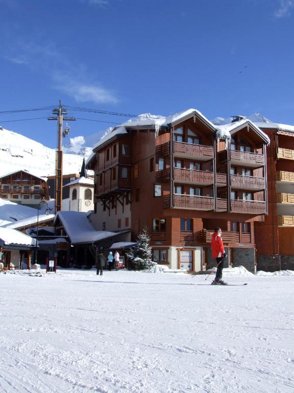 une personne à skis dans la neige devant un hôtel dans l'établissement Diamant Appartements VTI, à Val Thorens