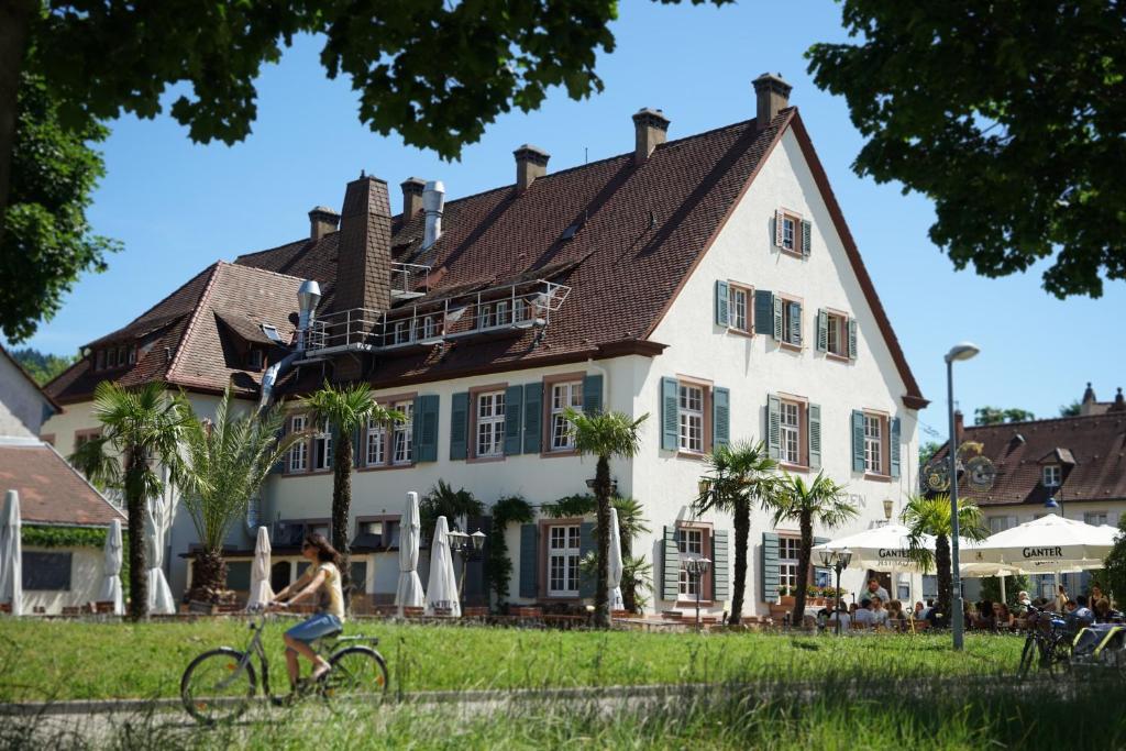 Una donna in bicicletta davanti a una casa di Hotel Gasthaus Schützen a Friburgo in Brisgovia