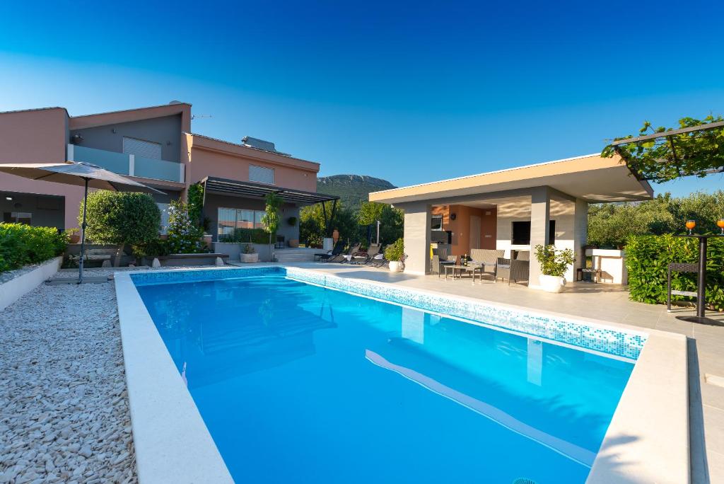 uma villa com uma piscina e uma casa em Villa Toni with 5 bedrooms and heated pool em Kaštela