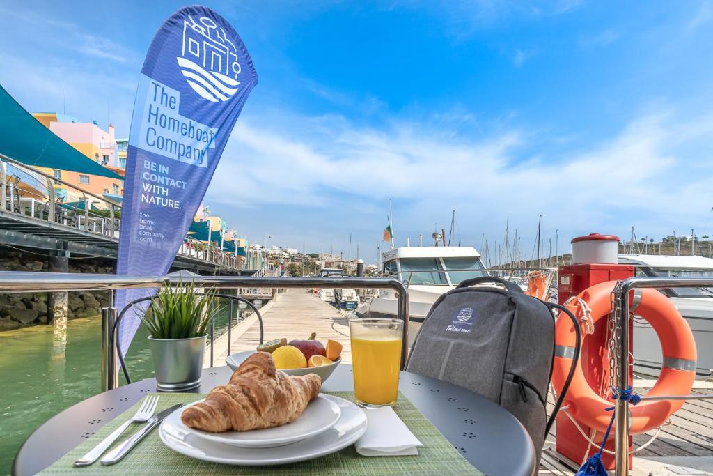 a table with a plate of food and orange juice at The Homeboat Company Albufeira in Albufeira