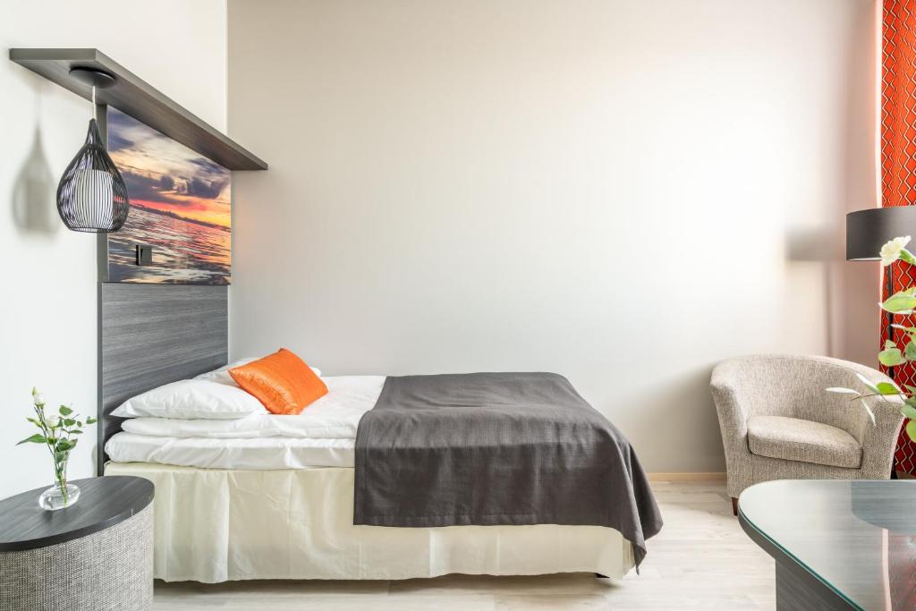 een slaapkamer met een bed en een stoel bij Hotelli Raahen Hovi in Raahe