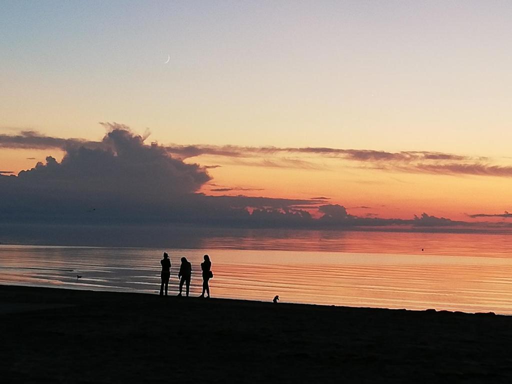 Tres personas de pie en la playa al atardecer en 15 minutes from the Beach and city Center 7 minutes from the airport, en Riga
