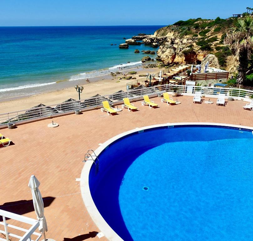 a swimming pool with chairs and a beach at Praia Oura Sunset in Albufeira