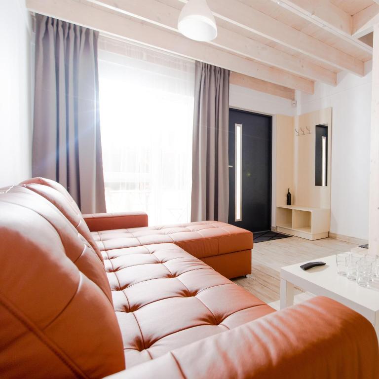 a living room with a leather couch and a large window at Pina House in Rewal