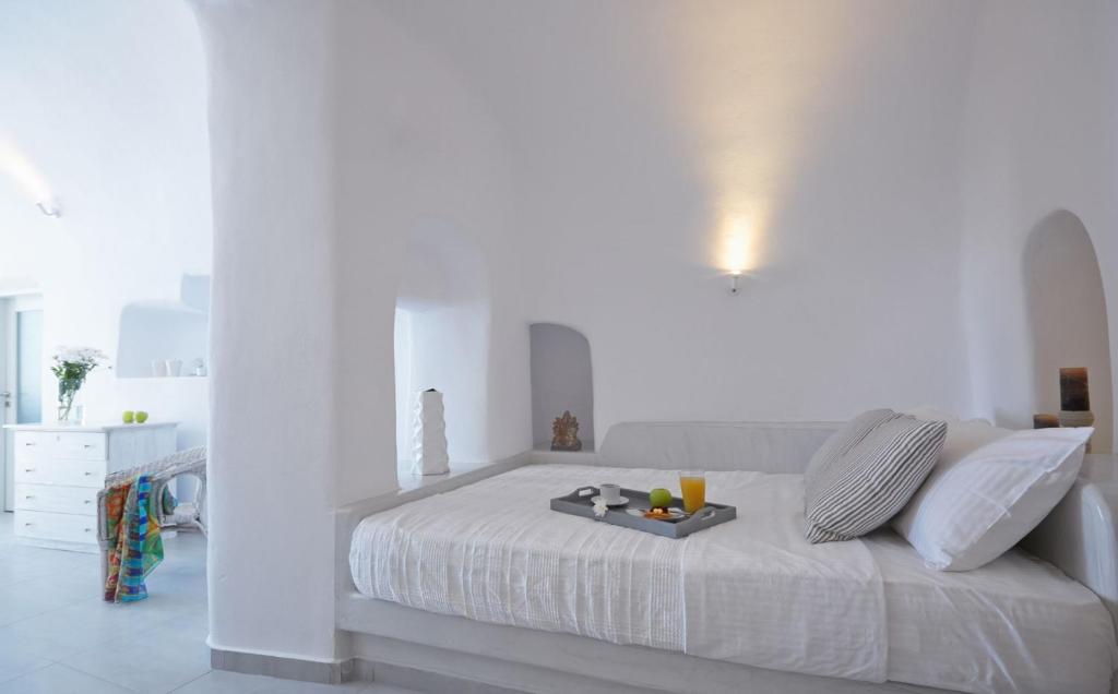 biała sypialnia z łóżkiem i tacą z owocami w obiekcie Amaya Castro Villa Caldera View-Outdoor Hot Tub Oia Santorini w mieście Thólos