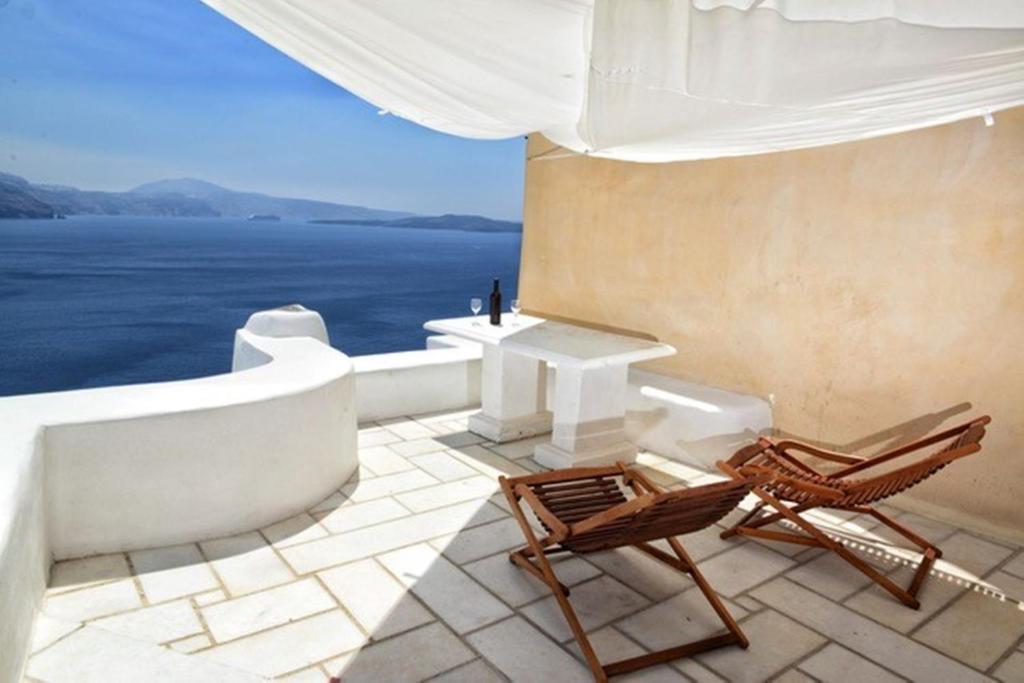 patio z 2 krzesłami i stołem oraz oceanem w obiekcie Amaya Bliss Villa Caldera View-Outdoor Hot Tub Oia Santorini w mieście Thólos