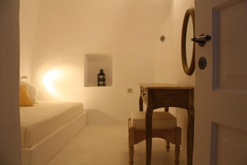 sypialnia z łóżkiem, stołem i lustrem w obiekcie Amaya Bliss Villa Caldera View-Outdoor Hot Tub Oia Santorini w mieście Thólos