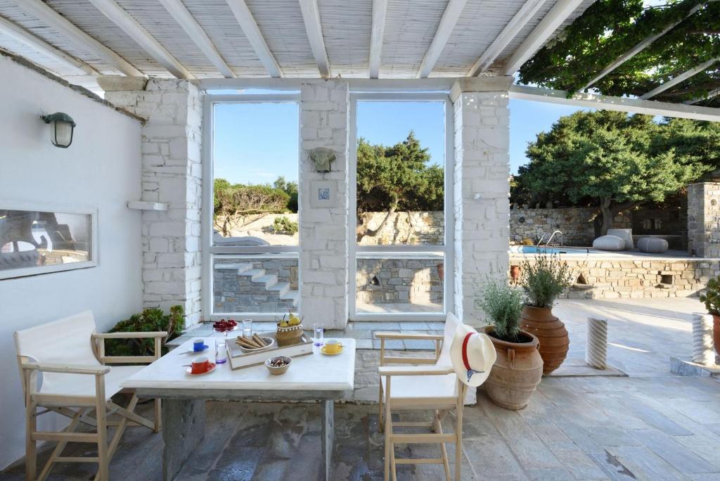 patio ze stołem i krzesłami oraz dużym oknem w obiekcie Villa Agia Thalassa Beachfront Luxury Villa Ampelas Paros w mieście Paros