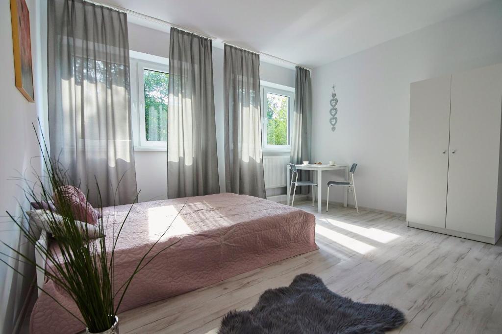 a bedroom with a bed and a table and windows at Regem Apartments Płońska in Warsaw