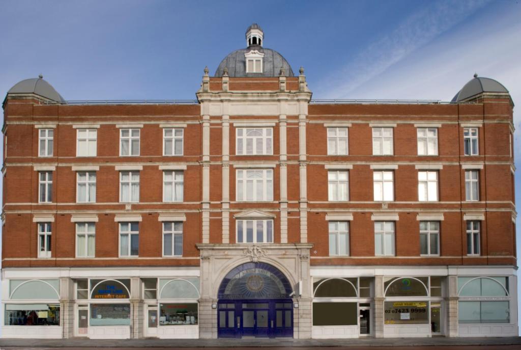 a large red brick building with a tower on top at Marlin Apartments Commercial Road - Limehouse in London