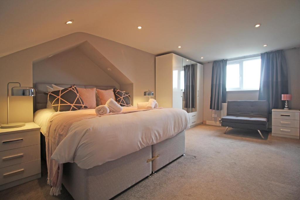 ein großes Schlafzimmer mit einem großen Bett und einem Stuhl in der Unterkunft Queens Road - Luxury Spacious Home in Chester in Christleton