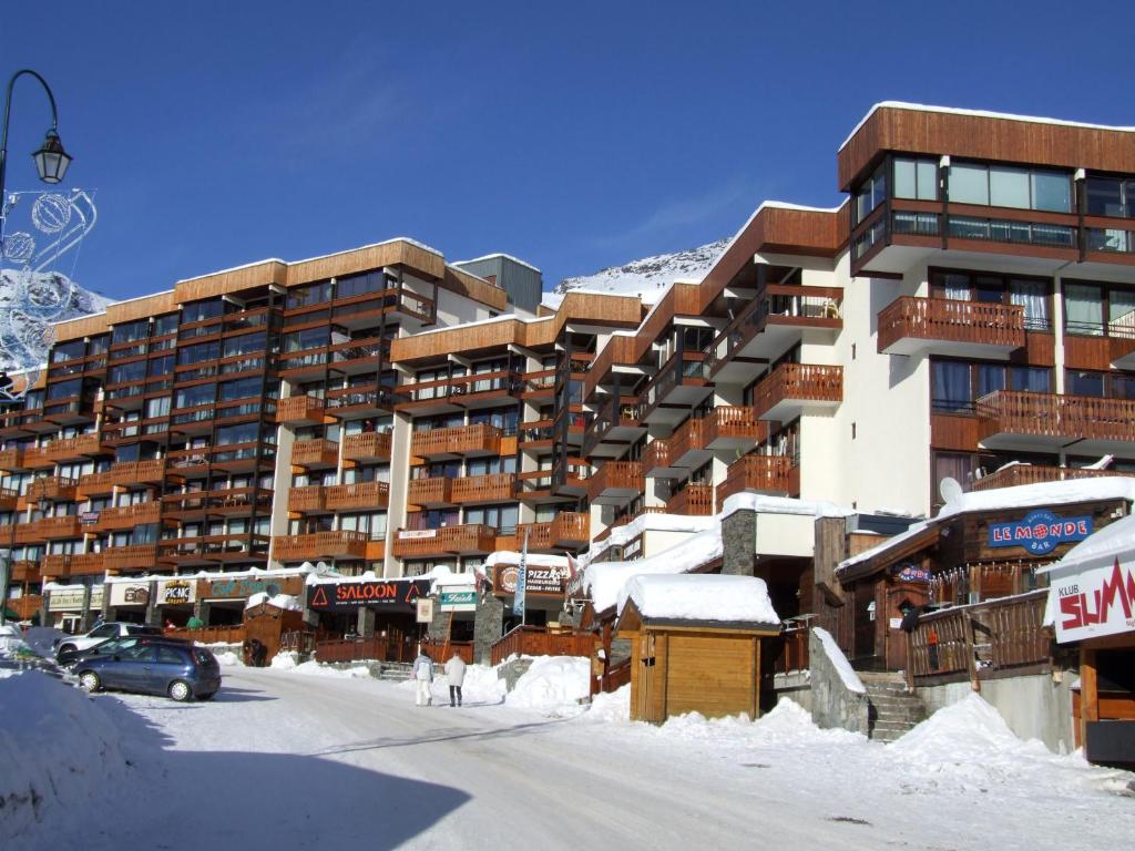 un grand immeuble avec de la neige au sol dans l'établissement Névés Appartements VTI, à Val Thorens