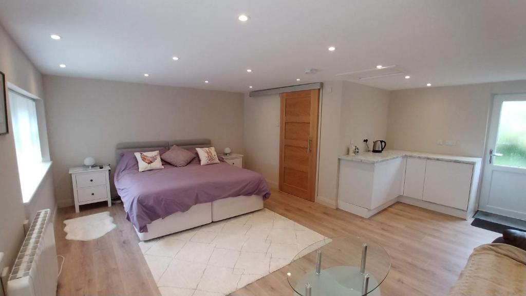 una camera da letto con un letto con lenzuola viola e un tavolo di The Garden Room, 1 Heath Cottage a Knutsford