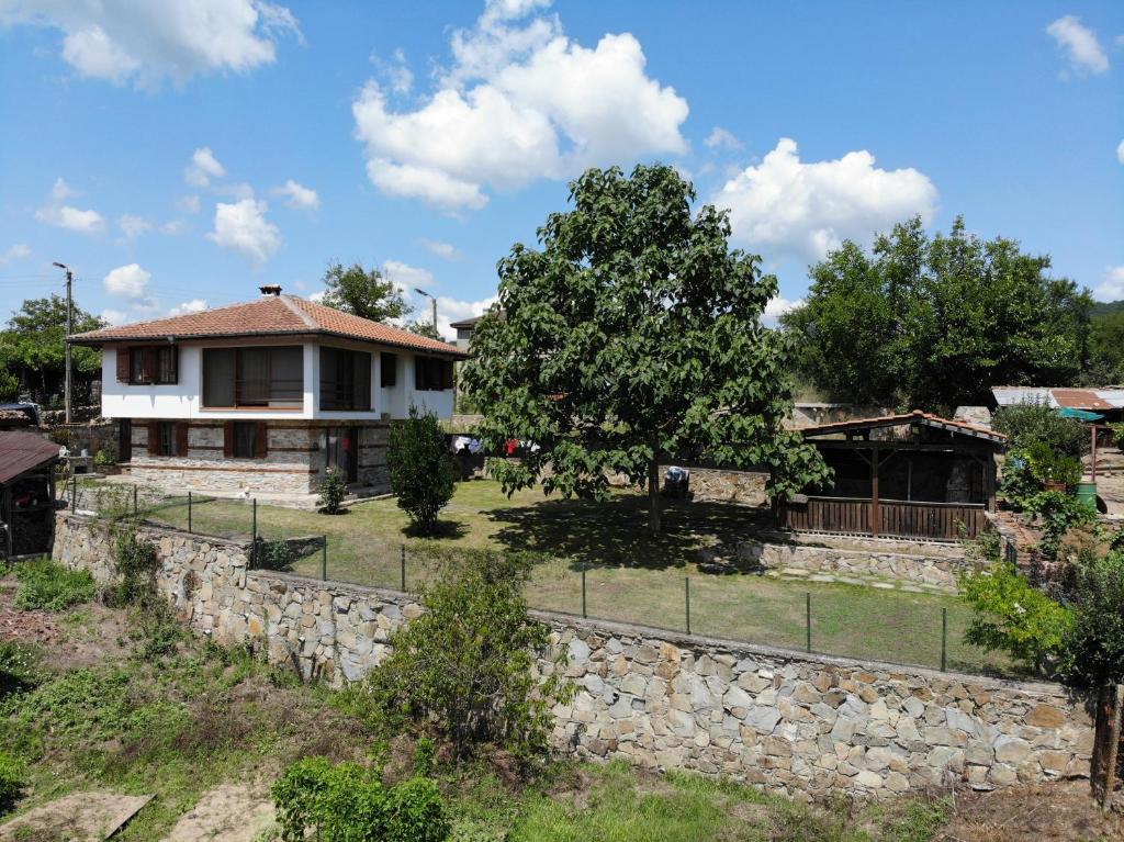 ein Haus mit einer Steinmauer und einem Baum in der Unterkunft Discover Strandja House in Kosti