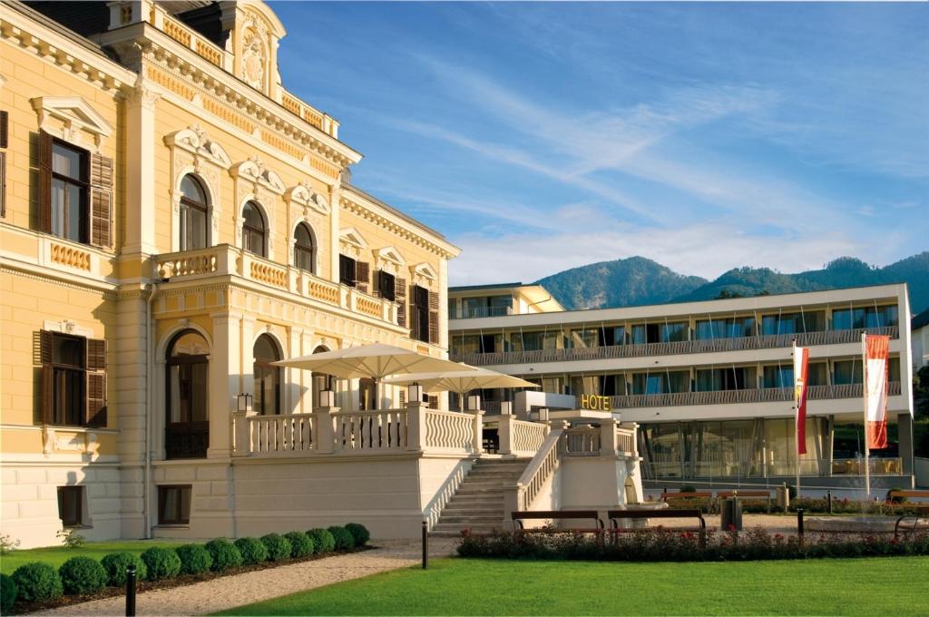 ein großes weißes Gebäude mit einem Tisch davor in der Unterkunft Villa Seilern Vital Resort in Bad Ischl