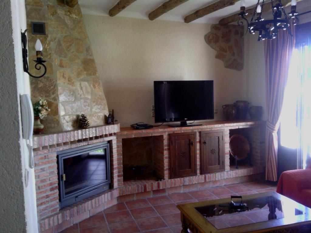 sala de estar con chimenea y TV de pantalla plana en Casa Rural-Apartamento El Lebrillero, en Zahara de la Sierra