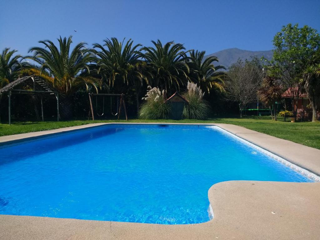 a large blue swimming pool in a yard with palm trees at Cabaña Mi Querencia in Olmué
