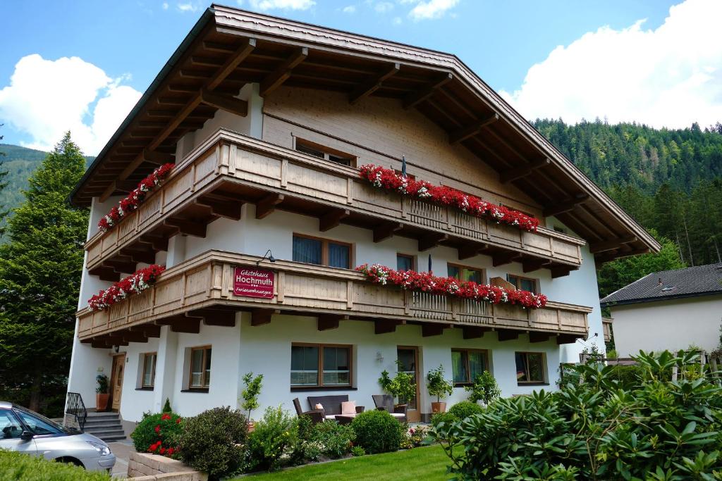 un edificio con un balcón con flores rojas. en Gästehaus Hochmuth, en Mayrhofen