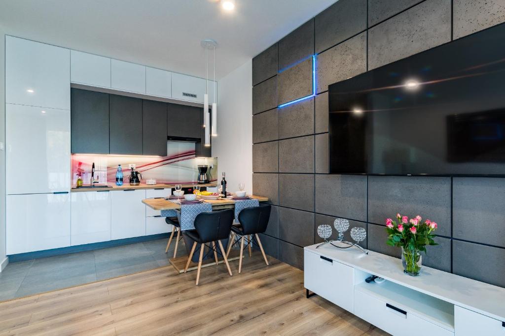 una cocina con armarios blancos y una mesa con sillas. en Apartament36-1c Calamo Park, en Olsztyn