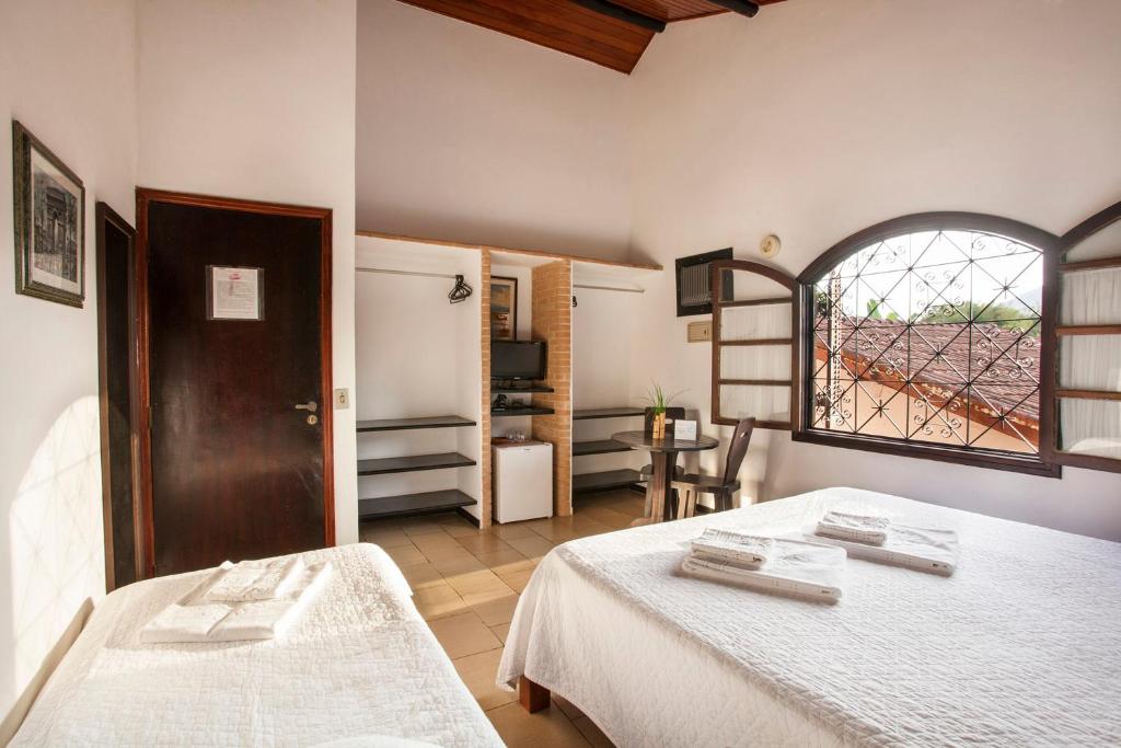 een grote kamer met 2 bedden en een raam bij Giprita Wellness Hotel Ubatuba in Ubatuba