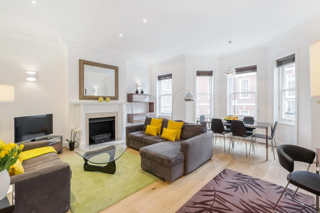 a living room with a couch and a fireplace at Chelsea - Draycott Place by Viridian Apartments in London