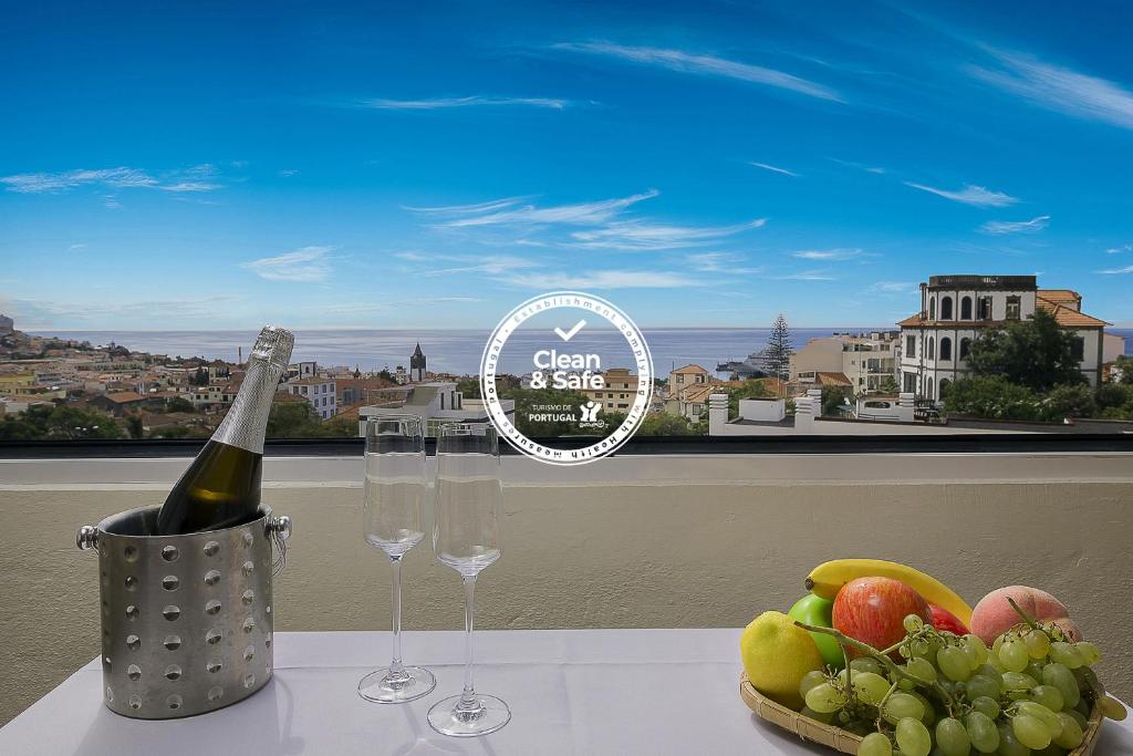 フンシャルにあるFunchal Window by Madeira Sun Travelのワイングラス2杯とフルーツプレート付きテーブル