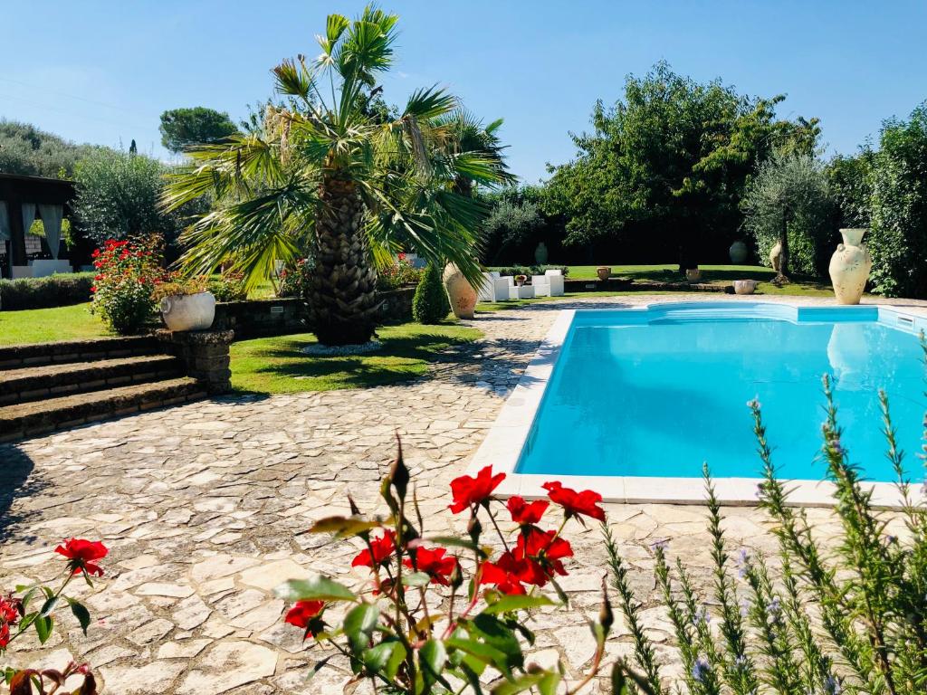 una piscina in un giardino con fiori rossi di VILLA "Casa al Chiazzullo" a Mirabella Eclano