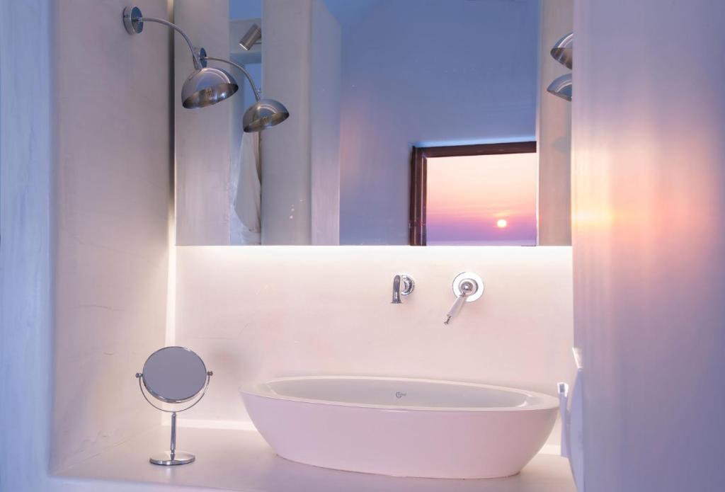 La salle de bains blanche est pourvue d'une baignoire et d'un miroir. dans l'établissement Luxury Santorini Villa Villa Pori Blanca Master Suite Private Pool and Stunning Sea View Near Pori Beach, à Foinikiá