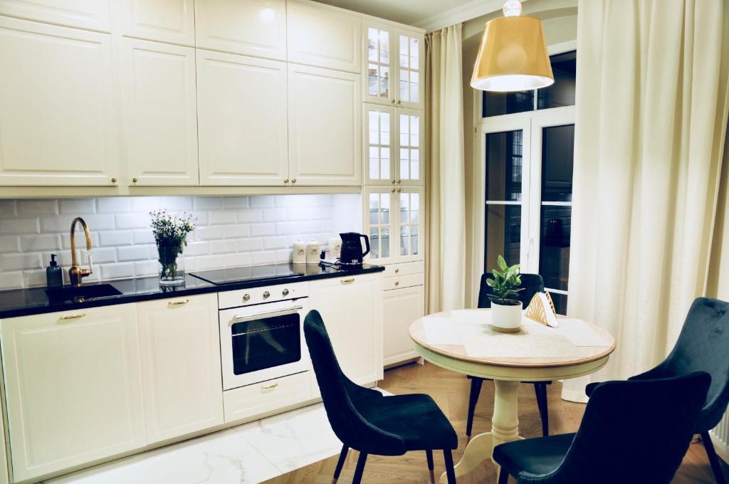 uma cozinha com armários brancos e uma mesa e cadeiras em GOLD APARTMENT Piotrkowska 37 em Lódź
