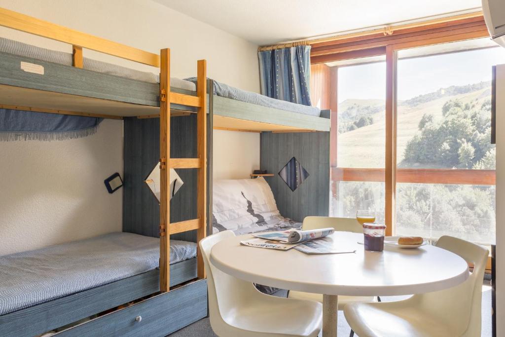 Cette chambre comprend une table et des lits superposés. dans l'établissement travelski home classic - Résidence Vanguard, au Corbier