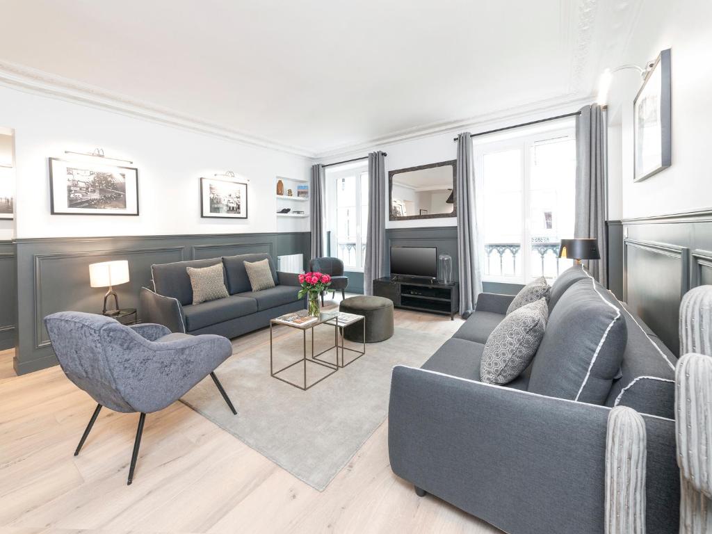 un soggiorno con divano grigio e sedie di LivinParis - Luxury 3 Bedrooms Le Louvre II a Parigi