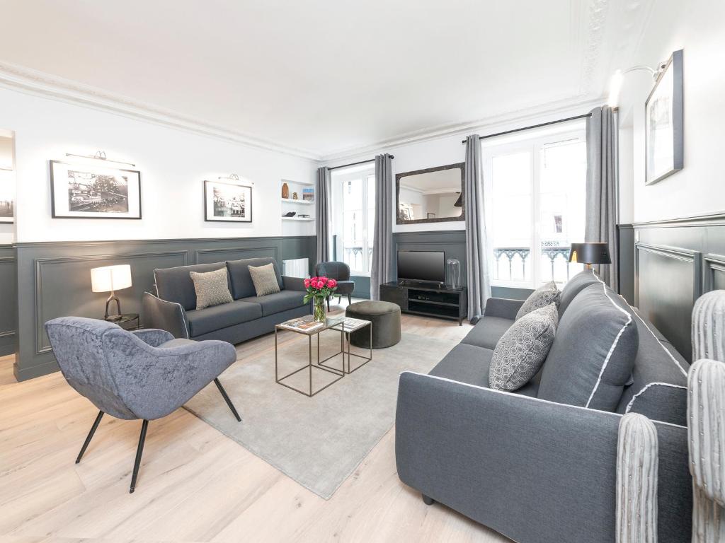 - un salon avec un canapé gris et des chaises dans l'établissement LivinParis - Luxury 3 Bedrooms Le Louvre II, à Paris