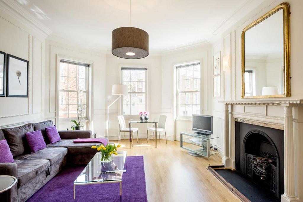 a living room with a couch and a fireplace at Chelsea - Sloane Avenue by Viridian Apartments in London