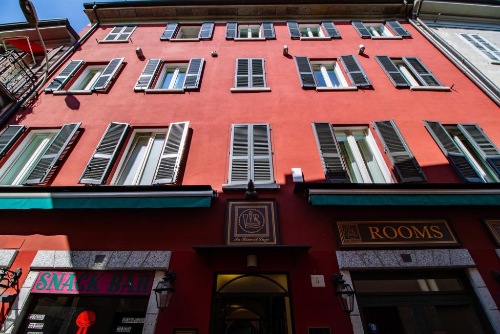 ein rotes Gebäude mit vielen Fenstern auf einer Straße in der Unterkunft In Riva Al Lago in Como